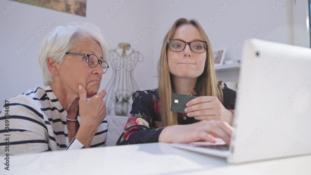 Young woman and senior lady shopping online and paying with credit card. slow motion. High quality 4k footage Young woman and senior lady shopping online and paying with credit card. slow motion. High quality 4k footage
