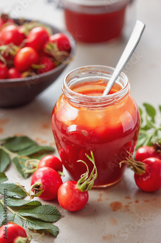 A jar of rose hip jelly and fresh rose hips