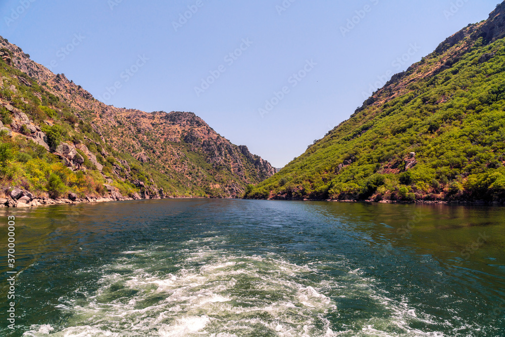wake in the water of a tourist cruise on a river between mountains in summer, between Spain and Portugal