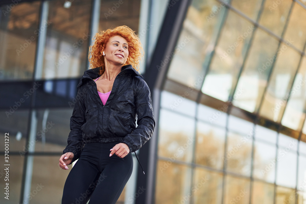 Young european redhead woman in sportive clothes doing fitness outdoors Young european redhead woman in sportive clothes doing fitness outdoors