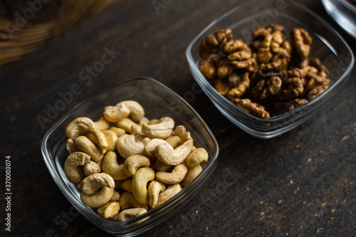 Almond, cachew and walnut in a small plates which standing on a black table. Nuts is a healthy vegetarian protein and nutritious food.