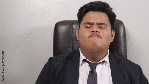 A funny Asian fat businessman wearing a suit look like the head of corporate executive or business manager listening to something, considering and concluded that he accepted and raise hand like.