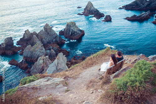 Couple contemplating the ocean from a bench