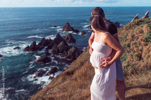 Pregnant couple on top of a cliff near the ocean