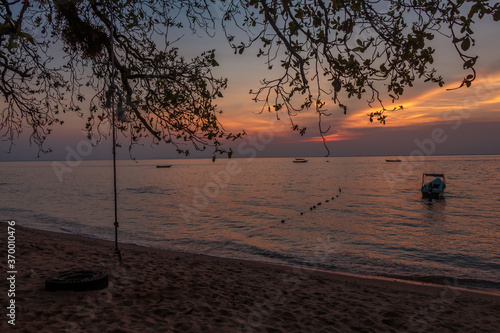 Rope swing and boat at sunset on Melina Beach, Tiomen Island photo