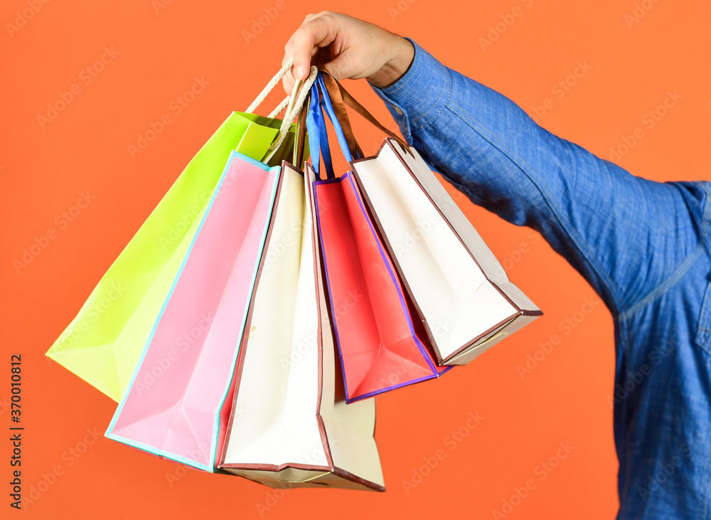 Hand hold bags. Shopping bags in hand on red background. Paper bags different colors. Shopping in mall. Black friday concept. Holidays preparation and celebration. Gift and present. Delivery