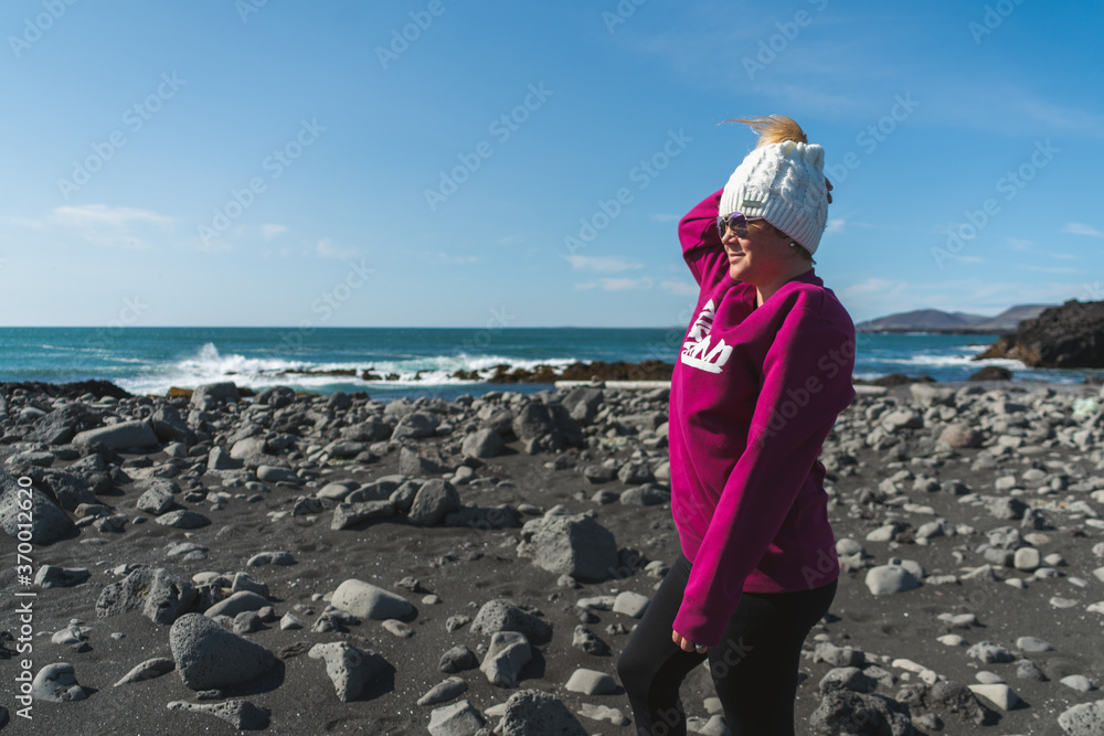 a woman standing at the black sand beach in Iceland