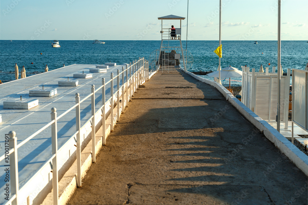 Pier with a lifeguard booth on the background of the sea