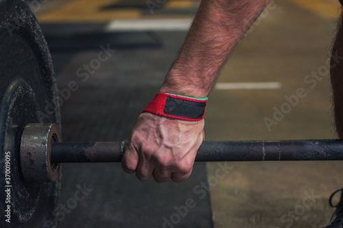 mano de atleta levantando barras con discos en el gimnasio