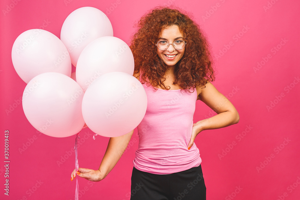 Happy holiday! Happy young curly smiling woman with balloons isolated over pink background. Valentine's day or woman's day. Happy holiday! Happy young curly smiling woman with balloons isolated over pink background. Valentine's day or woman's day.
