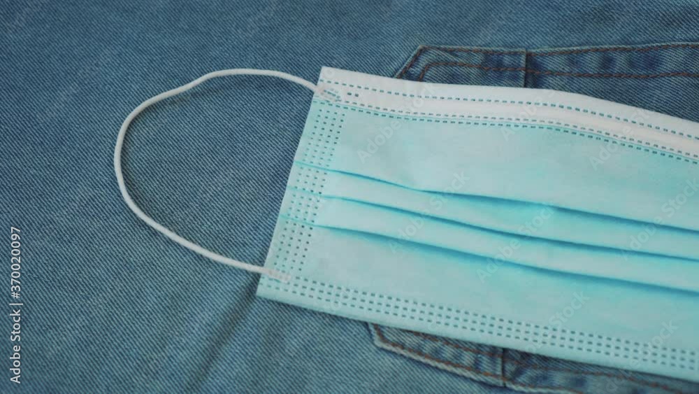 Medical mask on a blue back denim pocket, protection and defense measures against bacteria, viruses, coronavirus pandemic. Personal bacterial safety concept Medical mask on a blue back denim pocket, protection and defense measures against bacteria, viruses, coronavirus pandemic. Personal bacterial safety concept