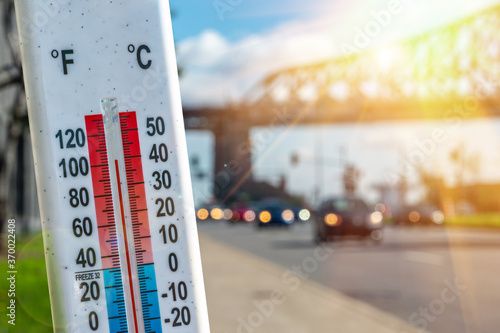 Thermometer in front of cars and traffic during heatwave in Montreal.