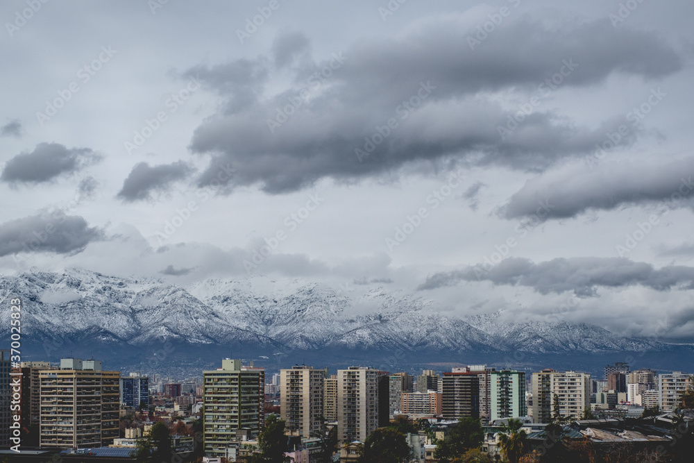 Amazing cloudy sky over Santiago skyline and the snowed Los Andes mountains, Chile