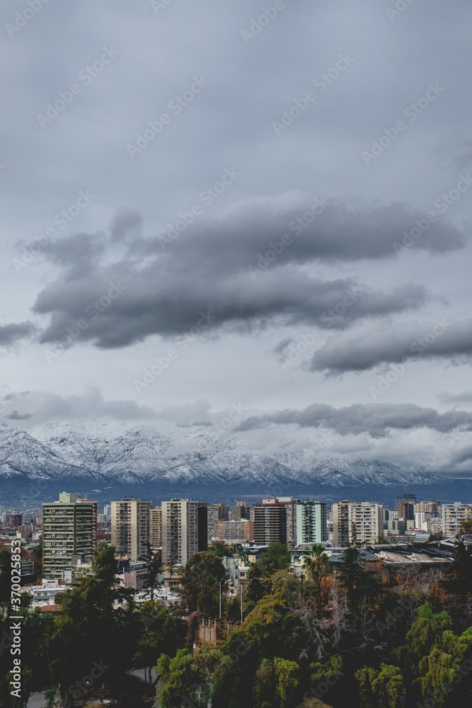 Amazing cloudy sky over Santiago skyline, Santa Lucía hill and the snowed Los Andes mountains, Chile