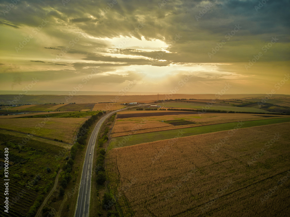 Aerial panorama over healthy green crops in patchwork pasture farmland. Magestic sunset.