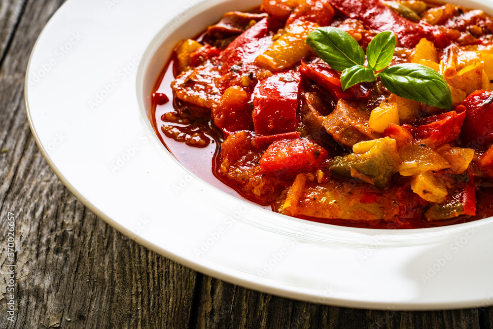Delicious stew - vegetable with sausages on wooden table Delicious stew - vegetable with sausages on wooden table