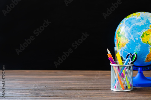 Back to school. School supplies and globe on black board background. Education concept.