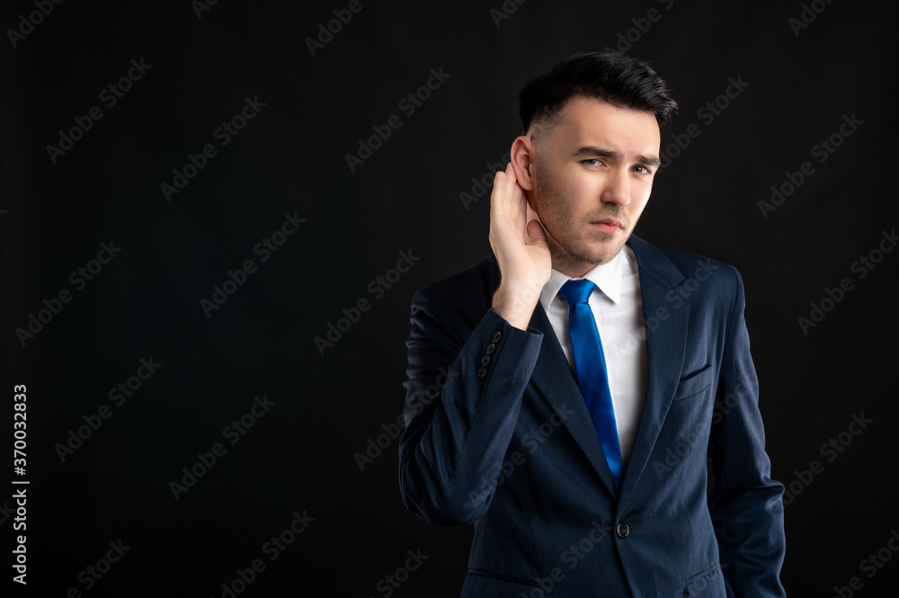 Portrait of business man wearing blue business suit and tie making can't hear you gesture Portrait of business man wearing blue business suit and tie making can't hear you gesture