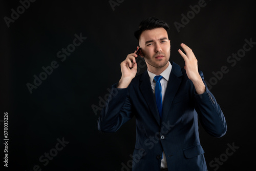 Portrait of angry business man wearing blue business suit and tie talking on the phone