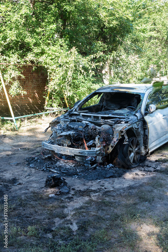 A burned-out car in the courtyard of a residential building. Fire in the car. Danger.