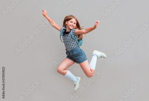 Full length photo of little pupil jump high finally holidays wear isolated on gray background © Яна Солодкая