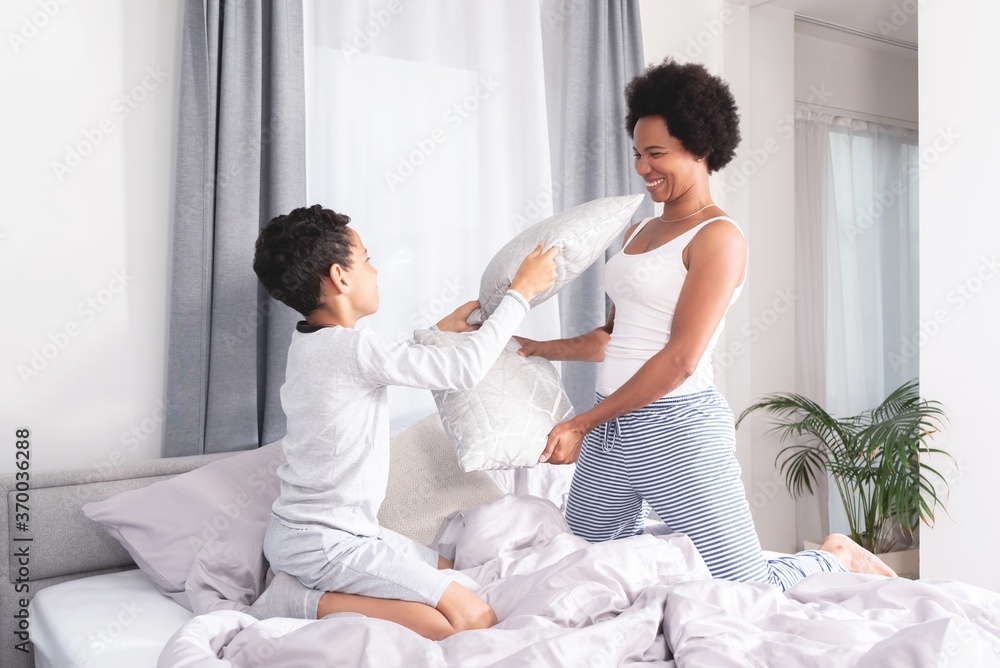 Playful mother and son fighting with pillow on bed Playful mother and son fighting with pillow on bed