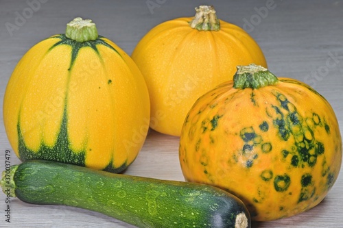 multicolored pumpkins next to zucchini in a peel on the table