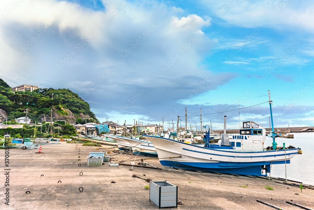 Fishing boats moored on the port of the Kanaya village in Futtsu city along the Uraga Channel with the cliffs of the Mount Nokogiri stone quarry in the Boso peninsula.