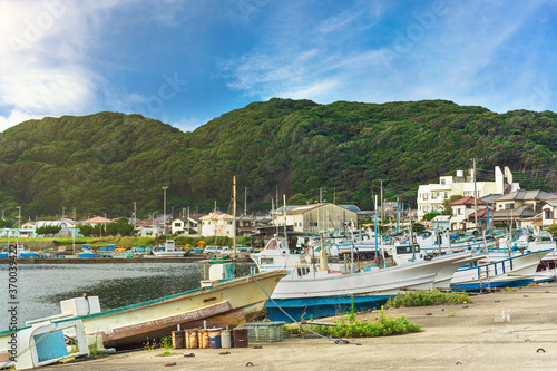 Fishing boats moored on the port of the Kanaya village in Futtsu city along the Uraga Channel with the cliffs of the Mount Nokogiri stone quarry in the Boso peninsula. photo