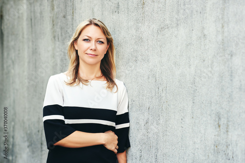 Bild auf Leinwand Outdoor portrait of middle age woman, leaning on grey wall