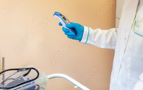 a device for measuring the pulse and rhythm in the hand of a female doctor in a blue glove and white coat and a stethoscope lying on the table photo