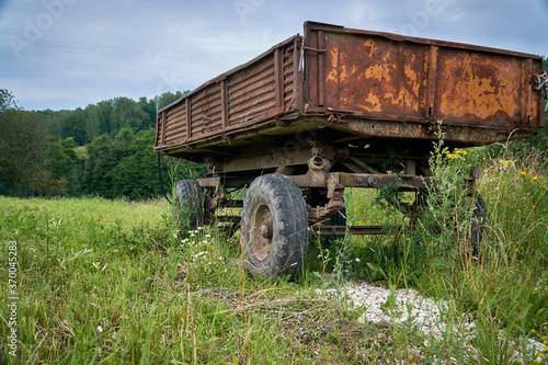 Abandoned old cargo trailer stands in a field on green grass. Close-up