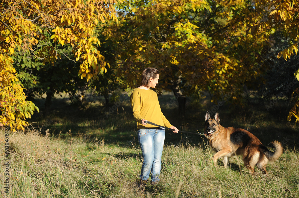 Happy woman walking in park with her german shepherd dog outdoor Happy woman walking in park with her german shepherd dog outdoor