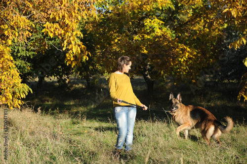 Happy woman walking in park with her german shepherd dog outdoor