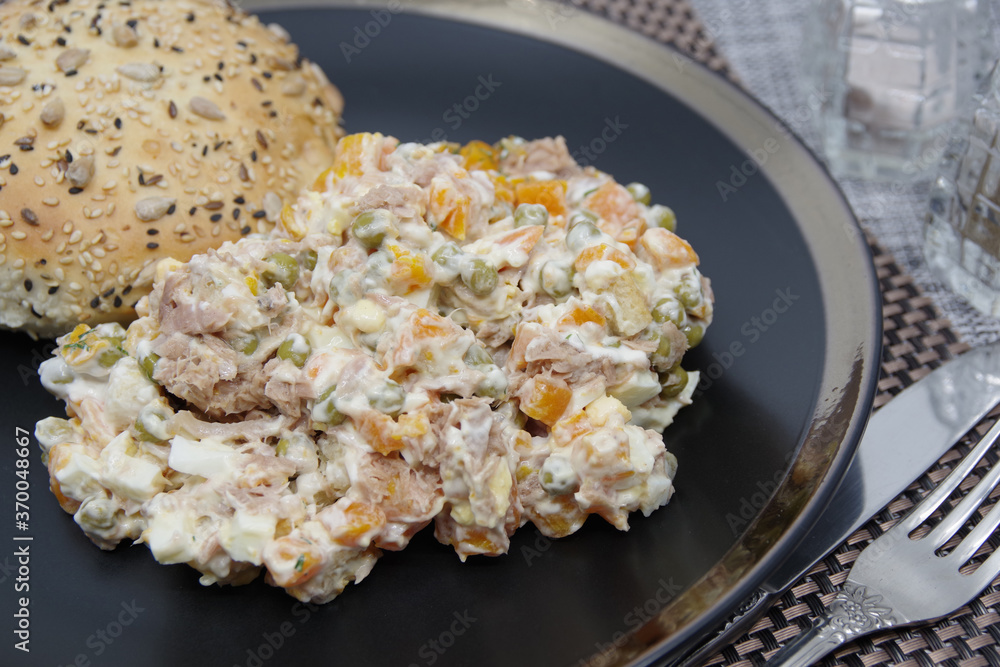 Tuna salad in black plate. Ingredients: tuna, carrots, eggs, onion, canned peas, croutons, mayonnaise Tuna salad in black plate. Ingredients: tuna, carrots, eggs, onion, canned peas, croutons, mayonnaise
