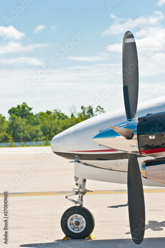 front view, close distance of the nose and propeller of a commercial, twin engine, airplane getting ready to take off from a tropical airport