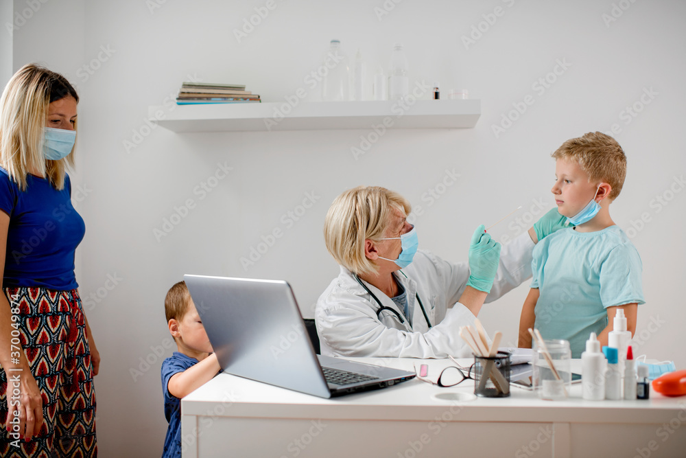 Female doctor performing a mouth swab test on a little child Female doctor performing a mouth swab test on a little child