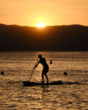 silhouette of a young man practicing paddle surf during the sunset in Cabo de Gata, Almeria