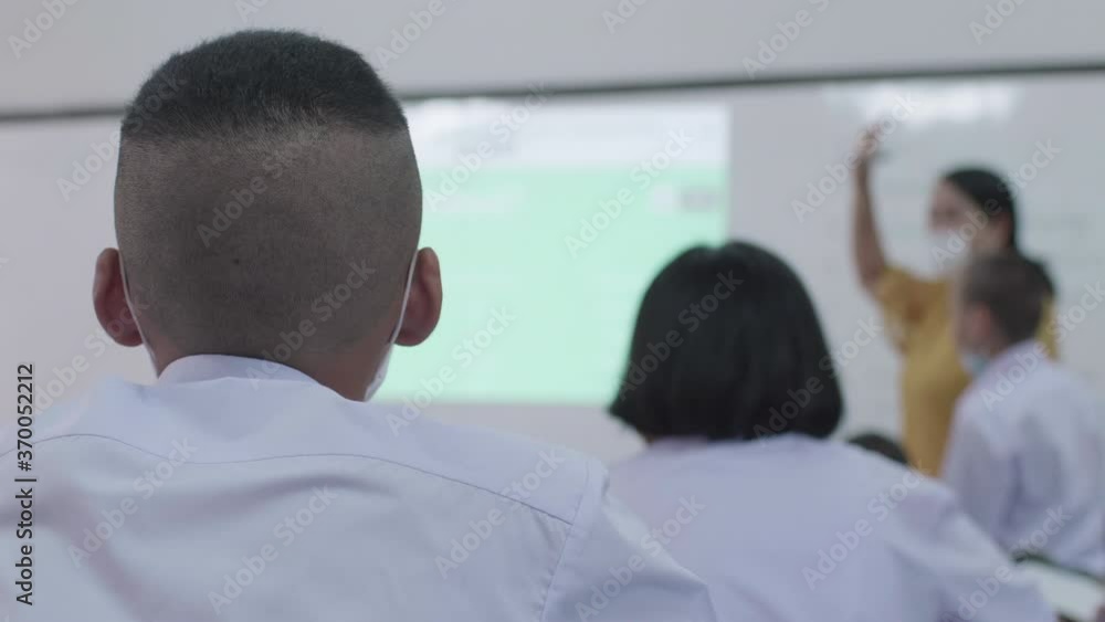 Slow motion of a Asian high school students in white uniform and wearing the mask are studying in classroom during the Coronavirus 2019 (Covid-19) epidemic. Slow motion of a Asian high school students in white uniform and wearing the mask are studying in classroom during the Coronavirus 2019 (Covid-19) epidemic.