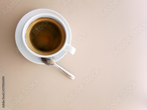 Top view of a paper cup of black coffee on ligth tone table
