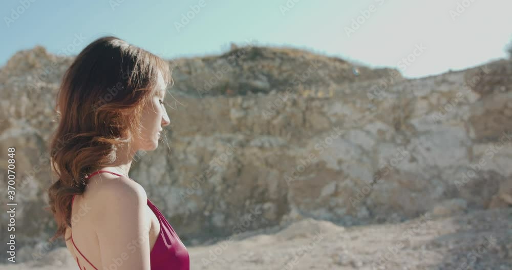 Closing view of woman in dress walking at cliffs in summer and looks at the sky Closing view of woman in dress walking at cliffs in summer and looks at the sky
