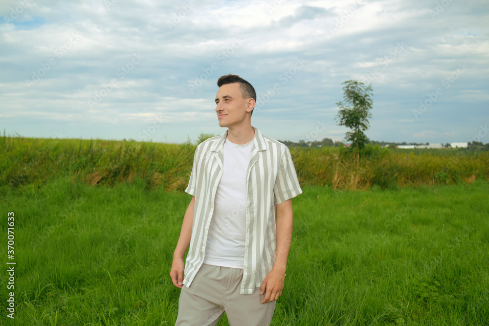 A fashionably dressed guy walking in a field outside the city. Man breathes fresh air, unity with nature A fashionably dressed guy walking in a field outside the city. Man breathes fresh air, unity with nature