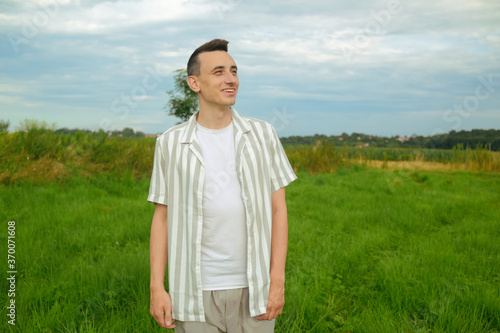 A fashionably dressed guy walking in a field outside the city. Man breathes fresh air, unity with nature