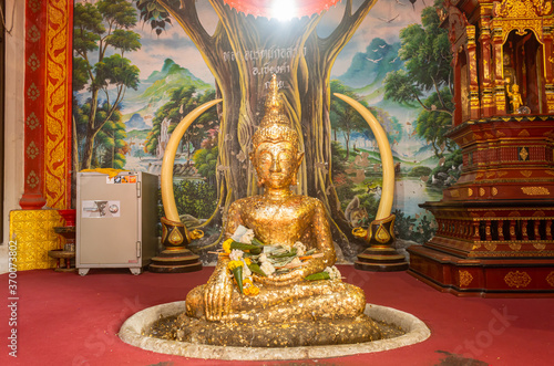 Phayao, Thailand - Dec 31, 2019: Gold Buddha Statue on Tree Painting Background in Wat Phra Nang Din or Phra Nang Din Temple at Chiang Kham District Phayao Thailand photo