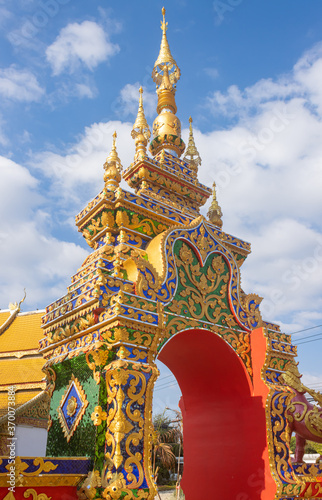Phayao, Thailand - Dec 31, 2019: Gold Pagoda or Stupa Entrance Door on Blue Sky Background in Portrait View in Wat Phra Nang Din or Phra Nang Din Temple at Chiang Kham District Phayao Thailand photo
