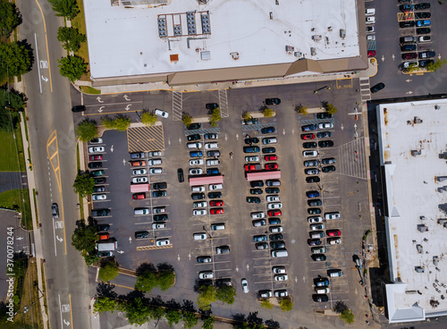The Parking lot is almost completely filled with colorful cars near on shopping center from the height of bird flight.