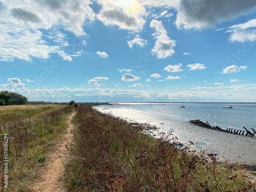 View of the broads National Park from the river bank in a cloudy day shoot taken against the sun with a dramatic sky and strong shadow.