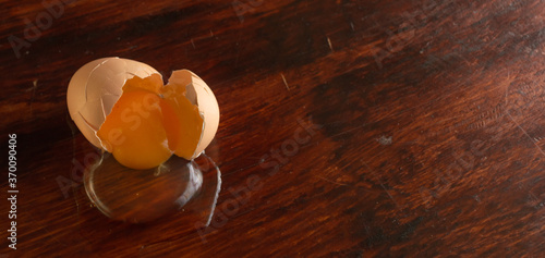 huevo café crudo roto sobre una mesa de madera barnizada
