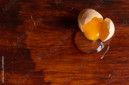 huevo café crudo roto sobre una mesa de madera barnizada