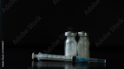 jeringas de tres mililitros con frascos de medicamento con polvo blanco en un fondo negro